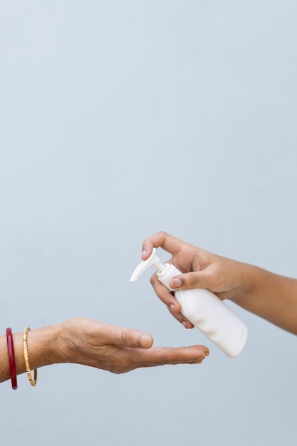 Primer plano de una persona vertiendo jabón líquido en la mano de otra persona