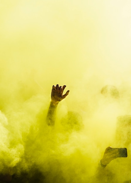 Primer plano de personas bailando y en explosión amarilla de color holi.