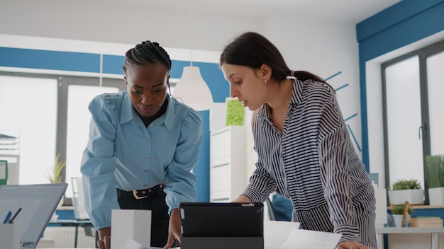 Primer plano de personas multiétnicas que trabajan con planes de planos para diseñar un edificio arquitectónico. Mujeres que usan tabletas digitales y planifican el diseño de la construcción con bocetos, lluvia de ideas.