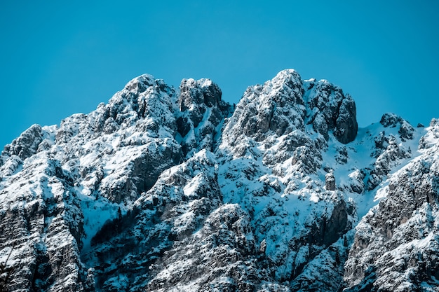 Primer plano de picos montañosos dentados cubiertos de nieve bajo un cielo azul claro