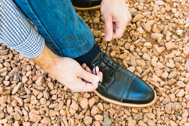 Foto gratuita primer plano del pie de un hombre sobre una piedra que ata el cordón del zapato