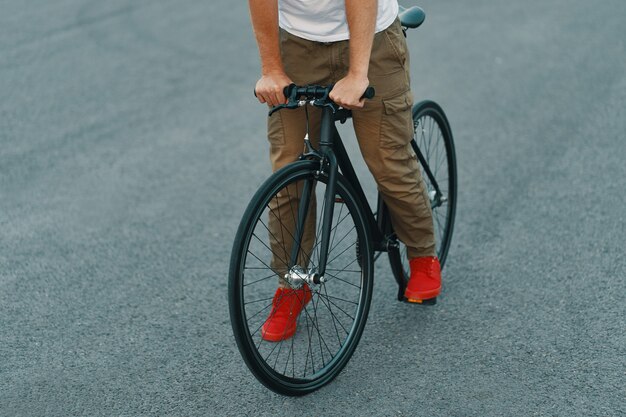 Primer plano de las piernas del hombre casual en bicicleta clásica en la carretera de la ciudad