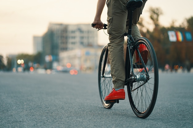 Foto gratuita primer plano de las piernas del hombre casual en bicicleta clásica en la carretera de la ciudad