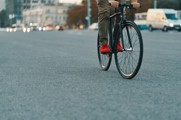 Primer plano de las piernas del hombre casual en bicicleta clásica en la carretera de la ciudad