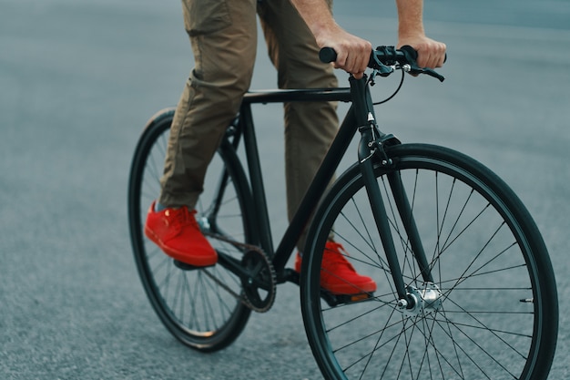 Primer plano de las piernas del hombre casual en bicicleta clásica en la carretera de la ciudad