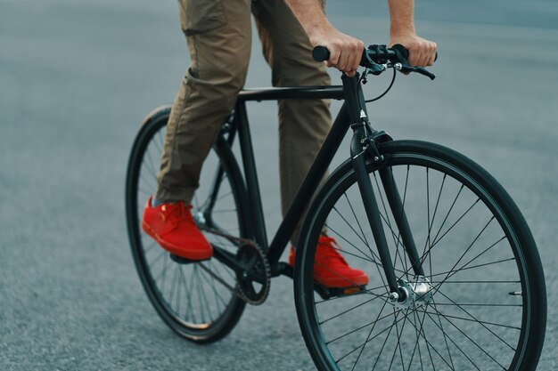 Primer plano de las piernas del hombre casual en bicicleta clásica en la carretera de la ciudad