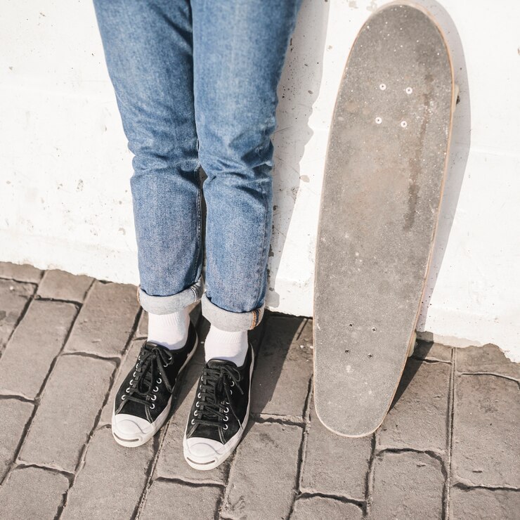 Foto gratuito primer plano de pies de skater con patín de pie delante de la pared