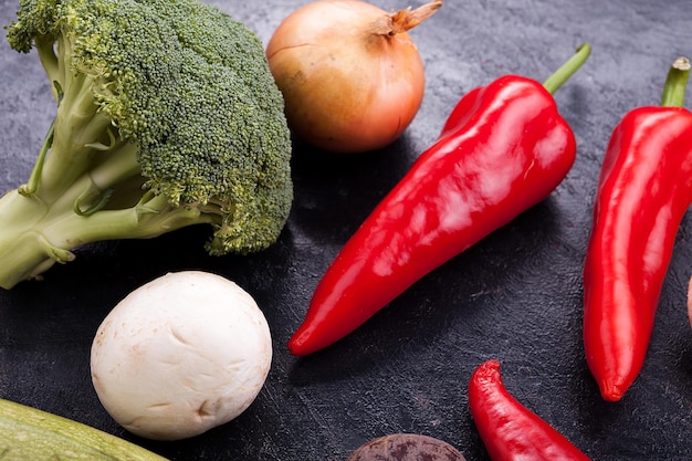 Primer plano de pimiento rojo dulce, brócoli, champiñones y cebolla en una mesa de madera vintage oscura