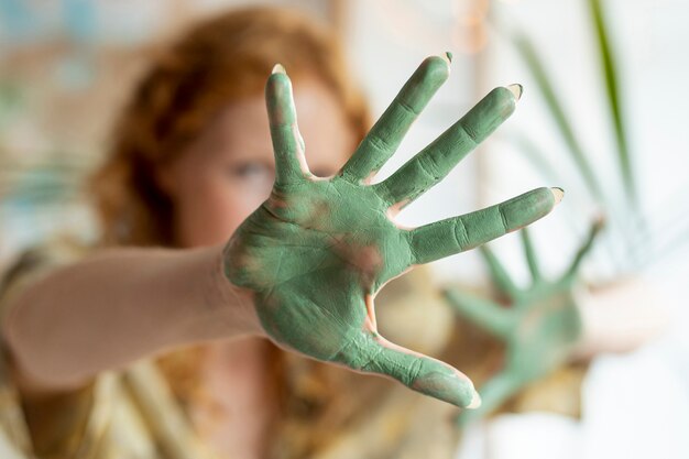 Primer plano de pintura verde en la palma de la mujer