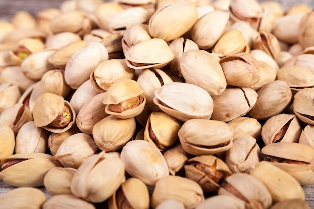 Foto gratuita primer plano de pistachos sobre fondo de madera en la foto de estudio. bocadillos saludables y deliciosos