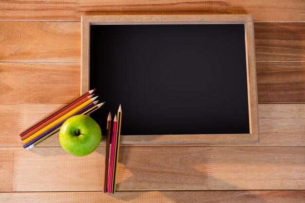 Primer plano de la pizarra con lápices de colores y manzana