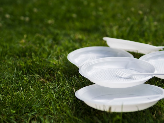 Foto gratuita primer plano de la placa de plástico blanco y tenedor sobre césped en el parque