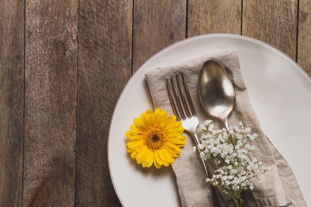 Primer plano de plato con cubiertos y decoración floral