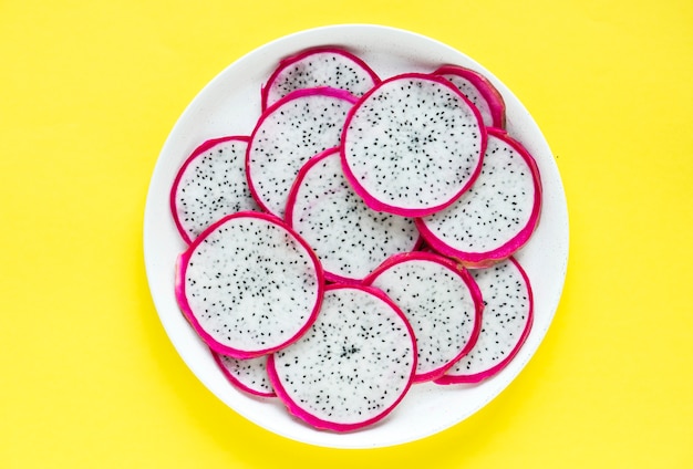 Foto gratuita primer plano de un plato de rodajas de fruta de dragón sobre fondo amarillo