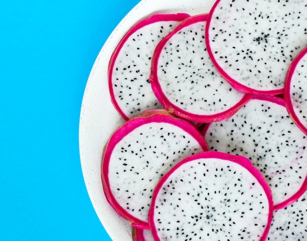 Primer plano de un plato de rodajas de fruta de dragón sobre fondo azul