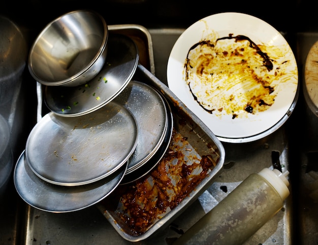 Primer plano de platos y bandejas usadas en el fregadero de la cocina del restaurante