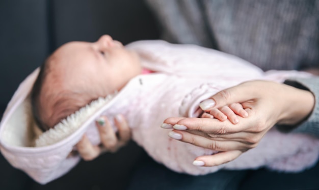 Primer plano de una pluma de una niña recién nacida en la mano de las mamás