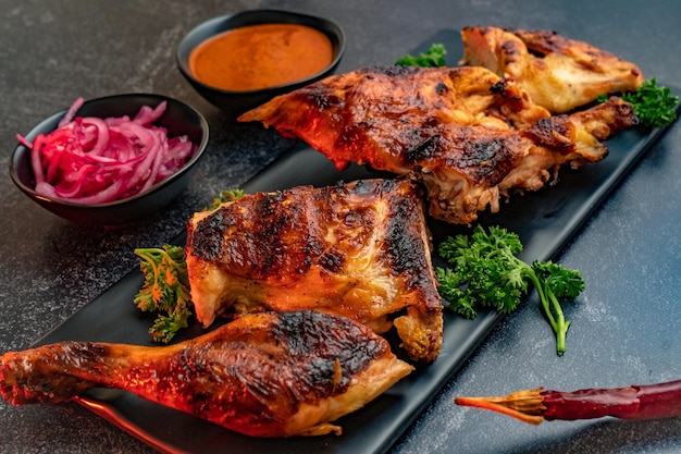 Primer plano de pollo deliciosamente preparado servido con cebolla y salsa picante