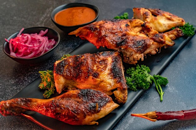 Primer plano de pollo deliciosamente preparado servido con cebolla y salsa picante