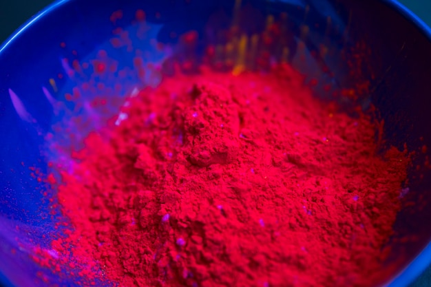 Primer plano de polvo de color rojo holi en el recipiente azul