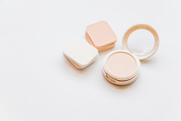 Primer plano de polvo compacto plástico realista cosmético con esponjas sobre fondo blanco