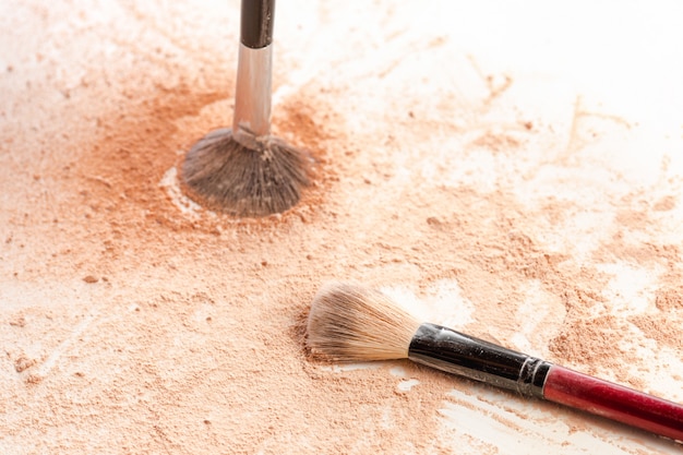 Primer plano de polvo mineral triturado brillo dorado con pincel de maquillaje