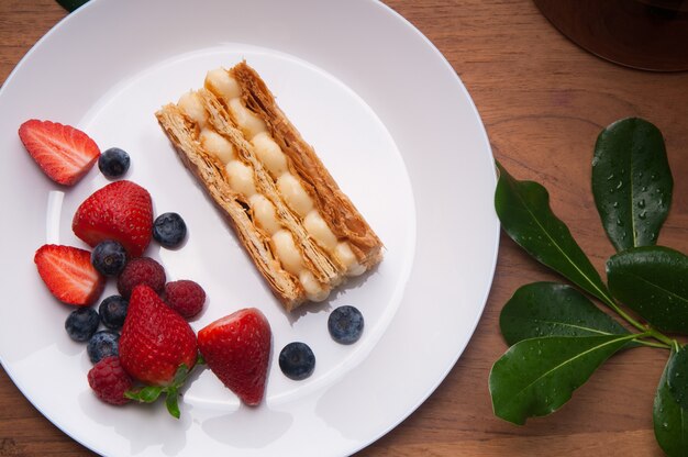 Primer plano de la porción de pastel y bayas frescas en un plato en la mesa