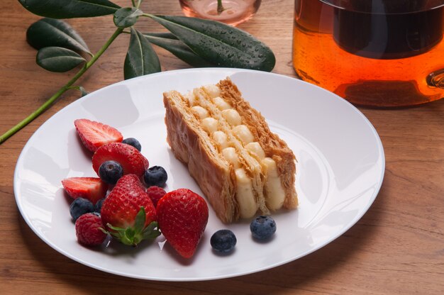 Primer plano de la porción de pastel de napoleón y bayas frescas en placa