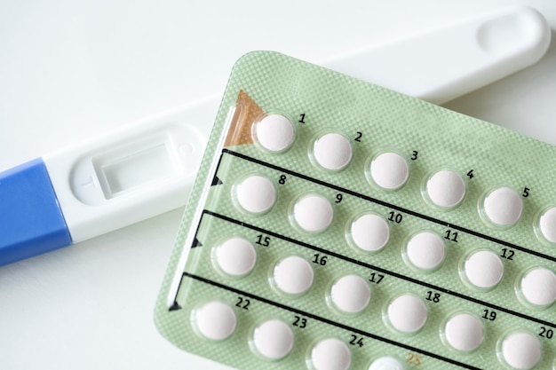 Primer plano de la prueba de embarazo y píldoras anticonceptivas concepto de control de la natalidad