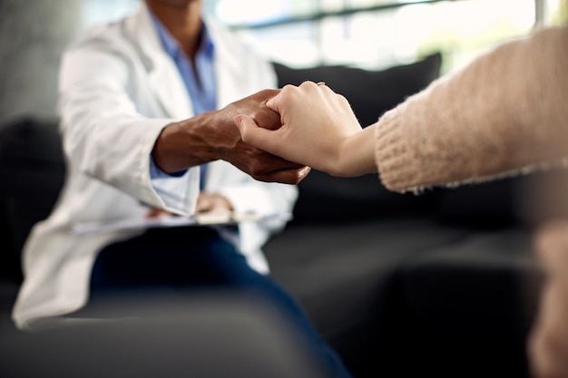 Primer plano de psicoterapeuta y su paciente tomándose de la mano durante una sesión