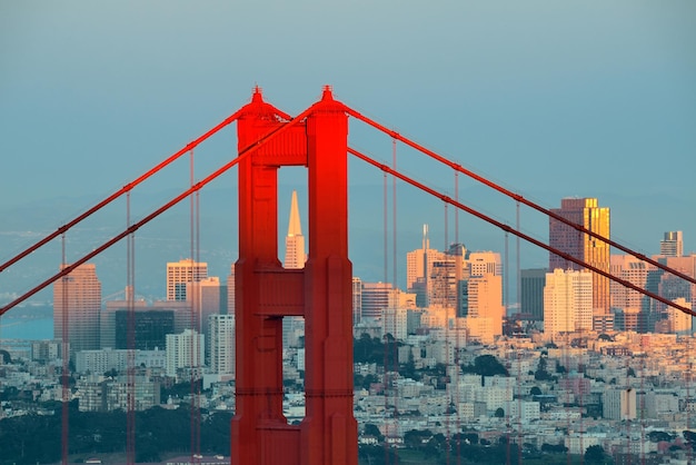 Primer plano del puente Golden Gate con el centro de San Francisco al atardecer.