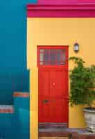 Foto gratuita primer plano de la puerta roja de un edificio amarillo y una planta junto a él