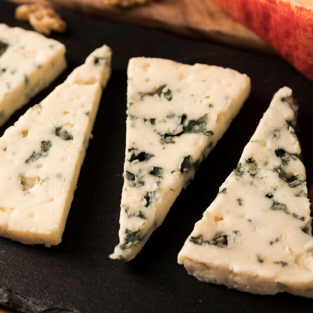 Primer plano de un queso azul dispuesto en pizarra de roca negra