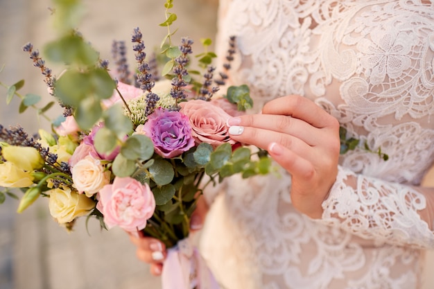 Primer plano de ramo de boda rosa y violeta en manos de la novia