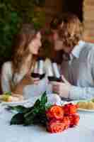 Foto gratuita primer plano de un ramo de flores con una pareja bebiendo vino