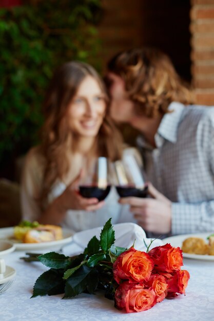 Primer plano de un ramo de flores con una pareja besándose