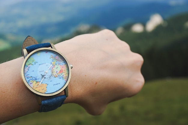 Foto gratuita primer plano de un reloj atado a una mano con mapa del mundo en él