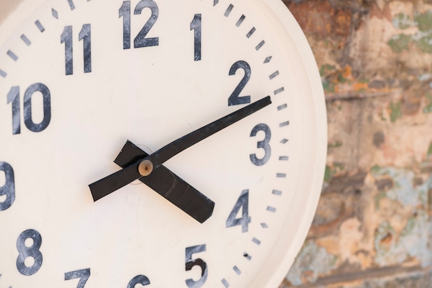 Primer plano de un reloj blanco en la pared desgastada