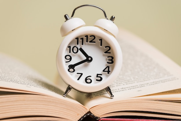 Foto gratuita primer plano de reloj despertador blanco en un libro abierto