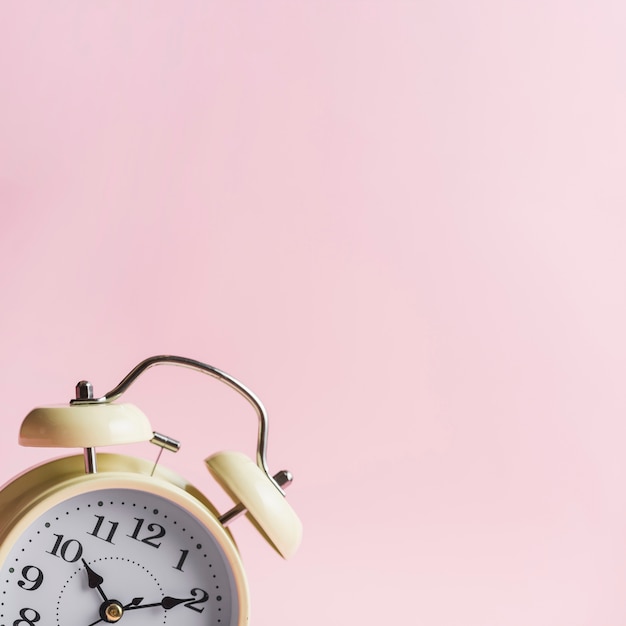 Primer plano de reloj despertador contra fondo rosa