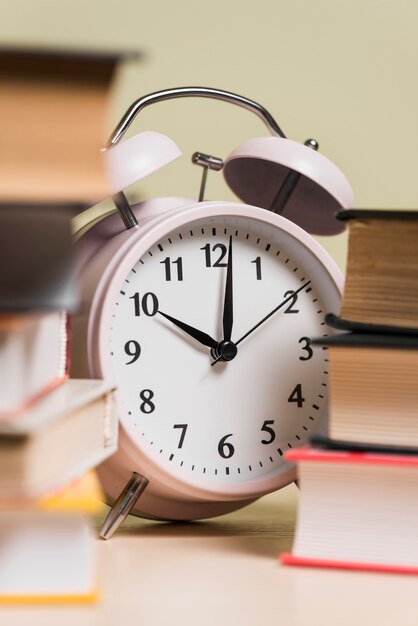 Primer plano de un reloj despertador y libros apilados