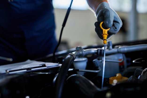 Foto gratuita primer plano de un reparador de automóviles que revisa el aceite del automóvil en un taller