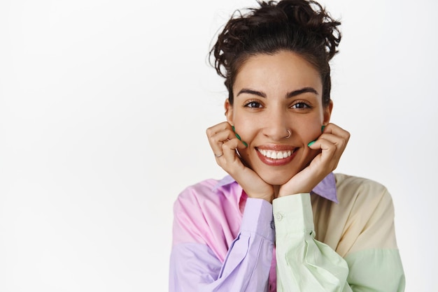 Primer plano retrato de cara de mujer feliz sonriente tomarse de la mano en la cara mirando a la cámara con cara alegre satisfecha ver algo interesante fondo blanco