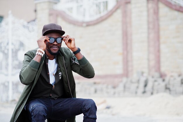 Primer plano retrato de elegante hombre afroamericano usar gafas de sol y gorra al aire libre Street fashion black man