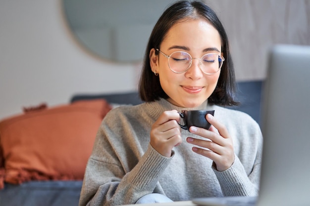 Foto gratuita primer plano retrato de hermosa mujer asiática bebe su café huele a bebida en taza toma freno de wo