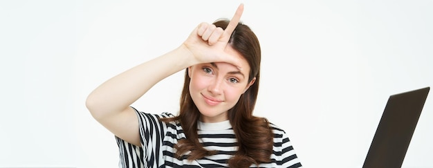 Foto gratuita primer plano retrato de una joven morena burlándose de ti mostrando el gesto de dedo perdedor l letra con la mano