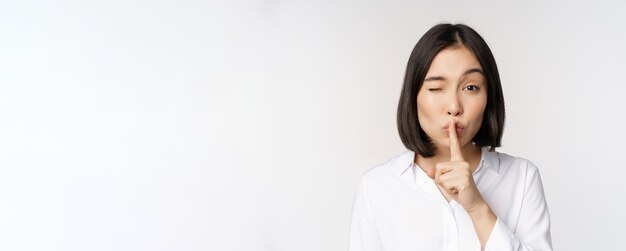 Primer plano retrato de mujer asiática joven haciendo silencio shhh shush signo presione el dedo a los labios no hable k