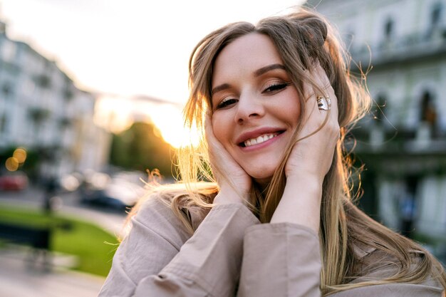 Primer plano retrato de mujer rubia feliz ciudad puesta de sol