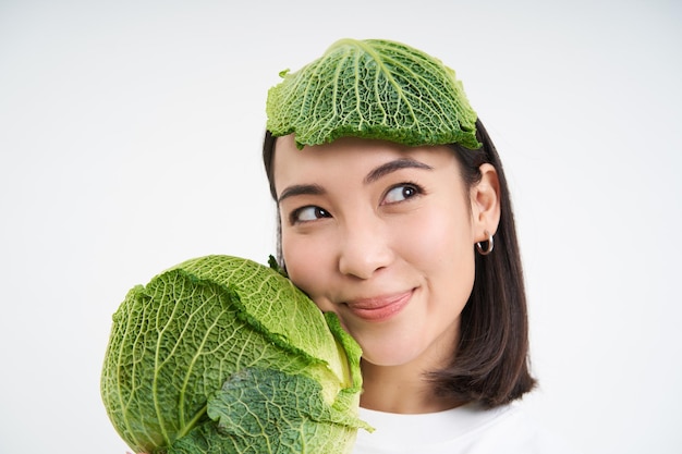 Foto gratuita primer plano retrato de mujer vegana hermosa y saludable sosteniendo lechuga tiene plomo de repollo en la cabeza con