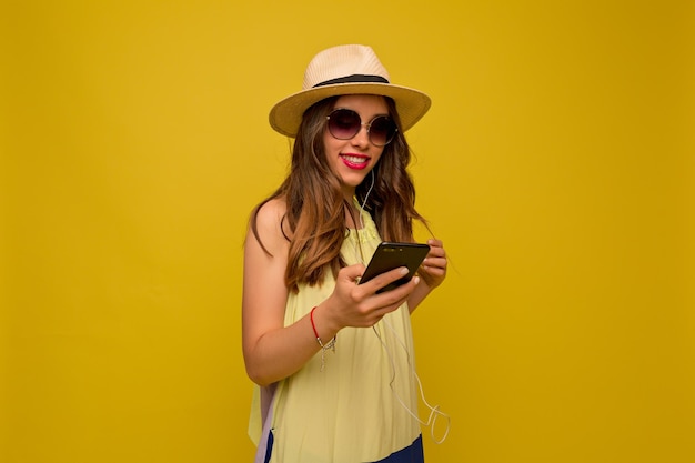 Foto gratuita primer plano retrato de niña feliz sonríe sobre piso amarillo mujer de cabello castaño con vestido amarillo de verano y sombrero sonríe ampliamente con los dientes buen humor concepto ocio